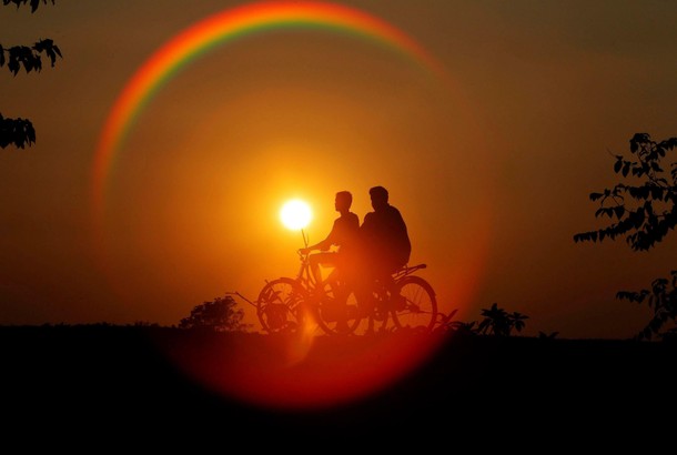 Boys are silhouetted against the setting sun as they ride bicycles on the outskirts of Agartala