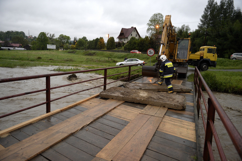 Strażacy obciążają betonowymi płytami most na wezbranej rzece Stupnica w Birczy, chcąc uchronić go przed zerwaniem przez wodę