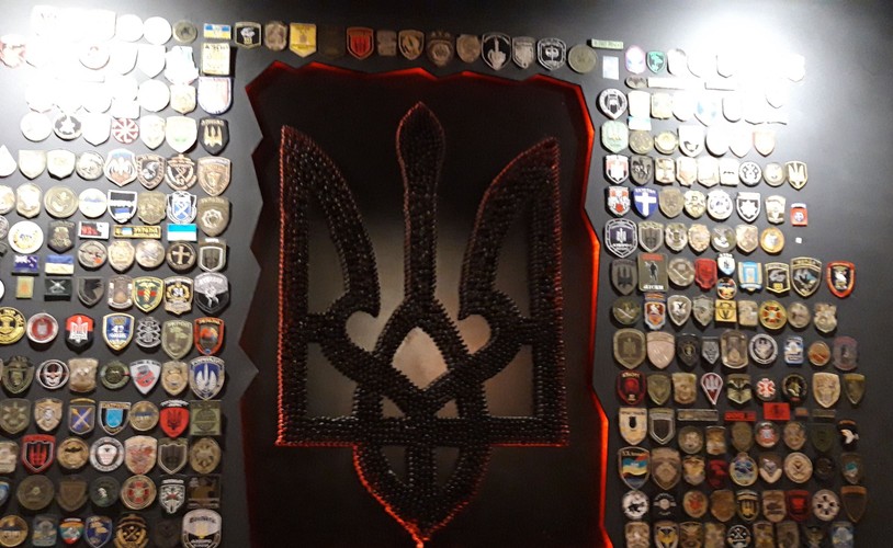 Herb Ukrainy wykonany z łusek, otoczony prawdziwymi naszywkami walczących batalionów. Pizza Veterano, prowadzona przez weteranów wojny w Donbasie