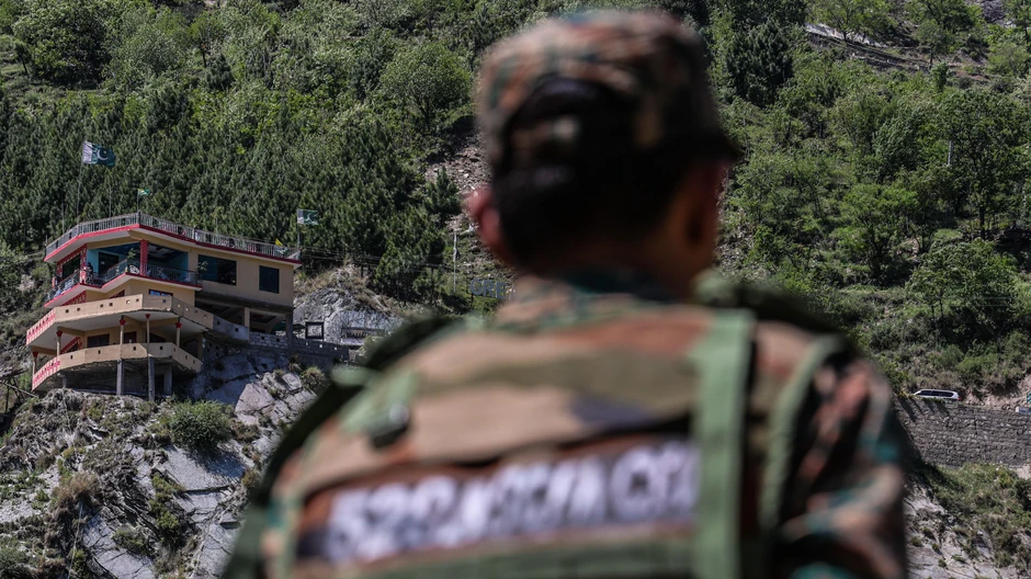 Pakistanska zastava i zgrade dok ih gleda vojnik u selu Simari na indijskoj strani Linije kontrole | Foto: Getty Images