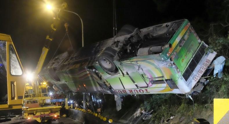 A bus that crashed along a highway is lifted by cranes in Taipei on February 14, 2017