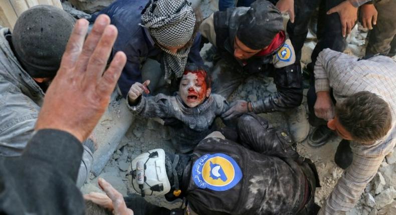 Syrian civil defence volunteers, known as the White Helmets, rescue a boy from the rubble following an attack on the Bab al-Nairab neighbourhood of Aleppo on November 24, 2016