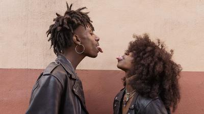 Young couple standing face to face and sticking out tongues [Image: Brian Jr Asare]