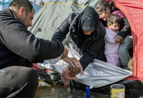 Wzruszające zdjęcie z obozu imigrantów. Dziecko myte w kałuży