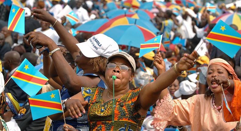 Kinshasa, Democratic Republic of the Congo: A woman waves the Congolese national flag during an inauguration ceremony for the new president Joseph Kabila, 06 December 2006, in Kinshasa. (Photo by LIONEL HEALING/AFP via Getty Images)