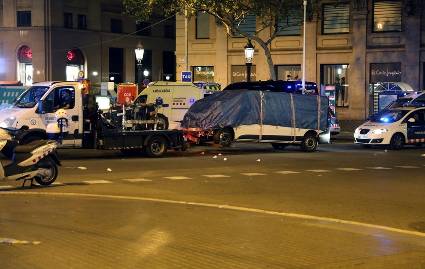 People help an injured woman after a van crashed into pedestrians near the Las Ramblas avenue in cen