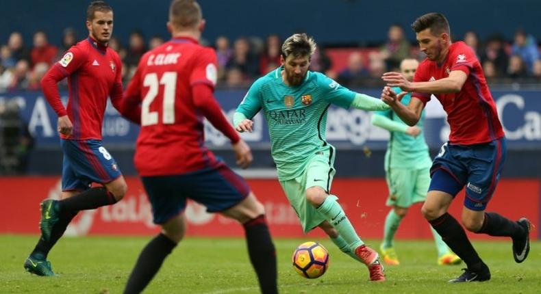 Barcelona's Argentinian forward Lionel Messi (centre) vies with Osasuna's defender David Garcia during their Spanish league match in Pamplona on December 10, 2016