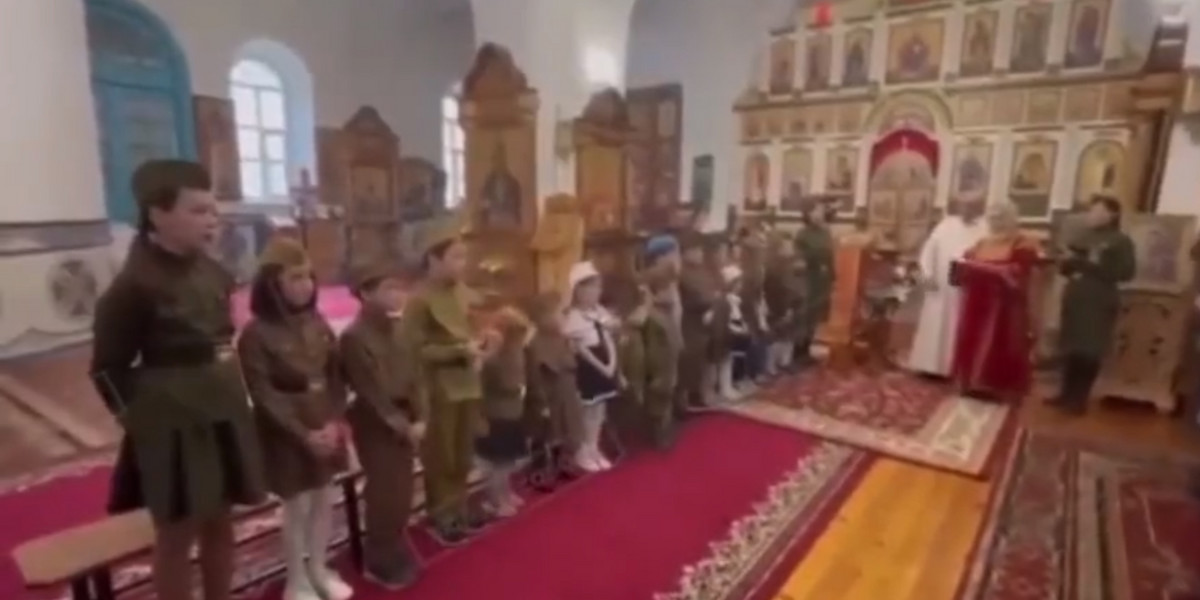 Grupa małych dzieci w rosyjskiej cerkwi przebrana w wojskowe mundury, śpiewała pieśni wojenne.
