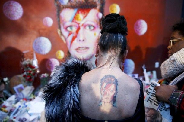 A woman with a Ziggy Stardust tattoo visits a mural of David Bowie in Brixton, south London