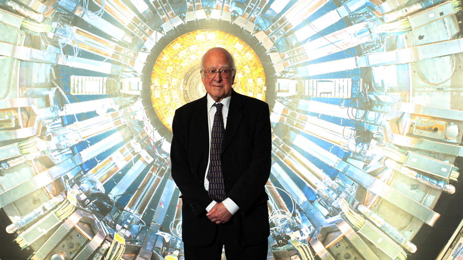 Peter Higgs w Muzeum Nauki w Londynie tuż przed otwarciem wystawy poświęconej Wielkiemu Zderzaczowi Hadronów, 12 listopada 2013 r. Zdjęcie w tle prezentuje jeden z detektorów, czyli "oczu" Zderzacza