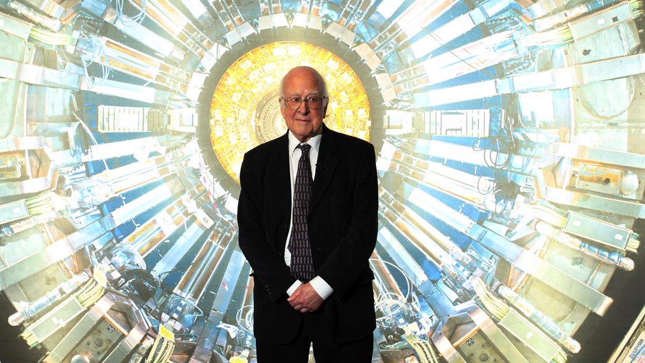 Peter Higgs w Muzeum Nauki w Londynie tuż przed otwarciem wystawy poświęconej Wielkiemu Zderzaczowi Hadronów, 12 listopada 2013 r. Zdjęcie w tle prezentuje jeden z detektorów, czyli "oczu" Zderzacza