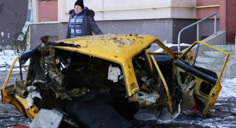 A woman walks past a destroyed car in Donetsk on February 9, 2017. Ukraine's case in The Hague accuses Russia of breaking a treaty by supporting pro-Russia rebels