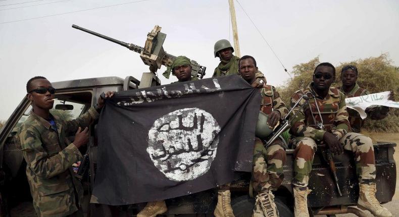 Nigerien soldiers hold up a Boko Haram flag that they had seized in the recently retaken town of Damasak, Nigeria, March 18, 2015.    REUTERS/Emmanuel Braun