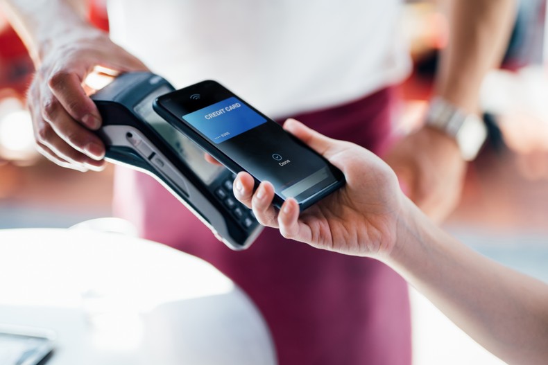 Close-up shot of a female hand using her smart phone to scan and pay for a bill at the restaurant during the day. Contactless payment, Technology Concept. [Stock Photo via Getty Images]