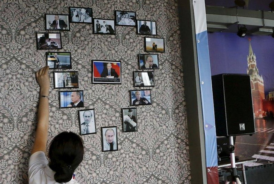 An employee of the "President Cafe" straightens portraits of Vladimir Putin hanging on the wall and arranged in the shape of a heart in Krasnoyarsk, Siberia, Russia, April 7, 2016.