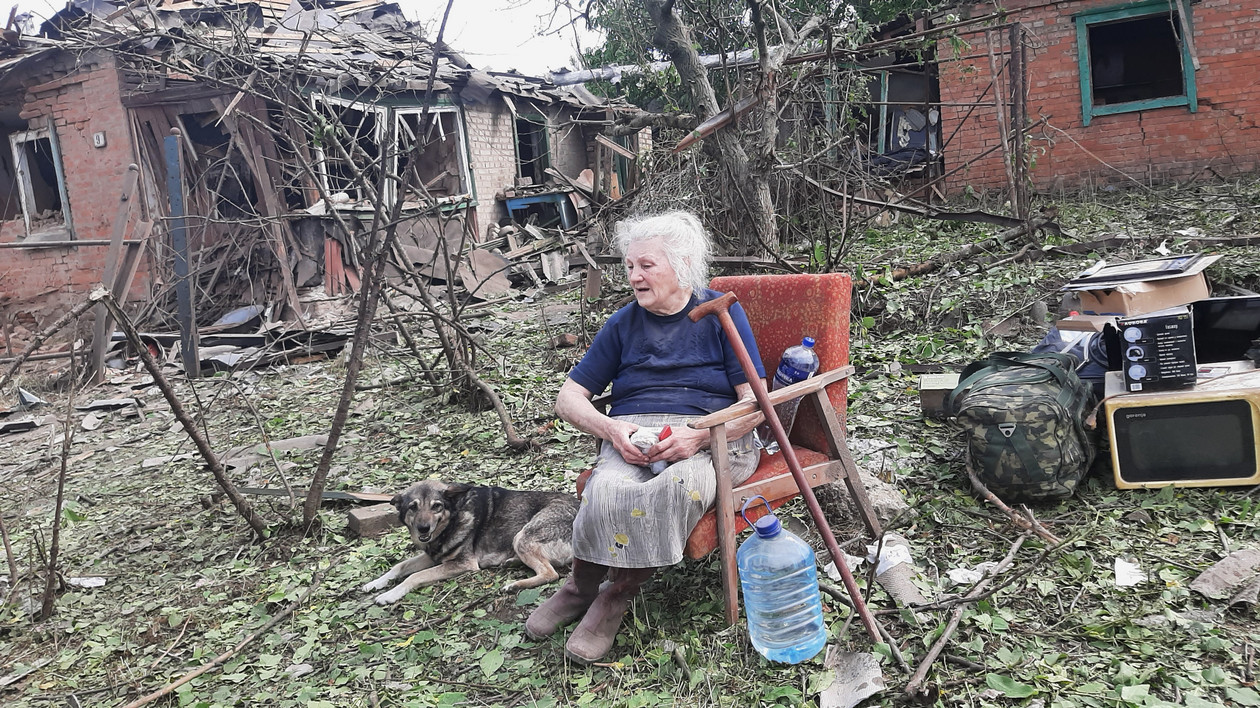 Kobieta z dobytkiem przed swoim zniszczonym domem w Drużkiwce.