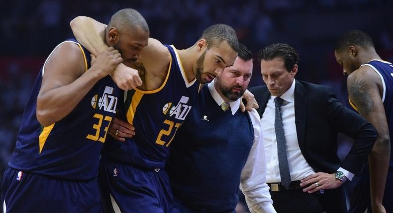 Rudy Gobert (C) of the Utah Jazz is helped off the court during the first half against the LA Clippers at Staples Center on April 15, 2017 in Los Angeles, California