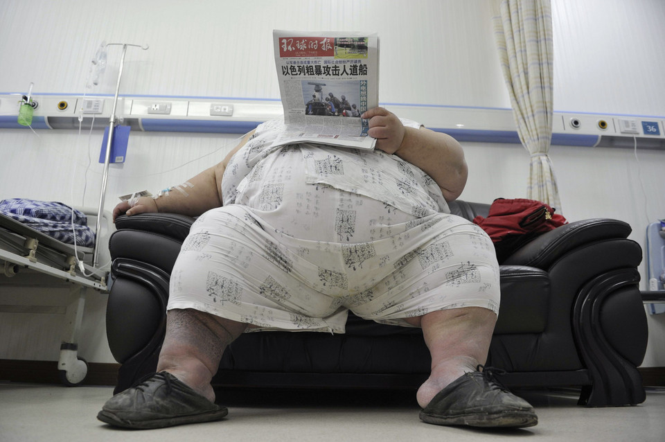 Liang Yong, 30, who weighs about 230 kg (507 lbs) and is 1.58 m (5.18 ft) tall, reads a newspaper in a ward at a hospital in Chongqing municipality June 1, 2010