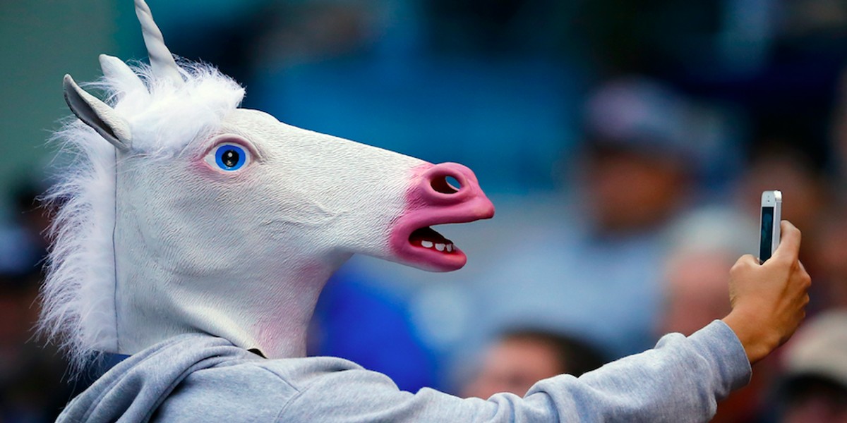 A baseball fan wearing a unicorn mask takes a picture of himself with his phone as he attends the Interleague MLB game between the San Diego Padres and the Toronto Blue Jays in San Diego, California June 2, 2013.