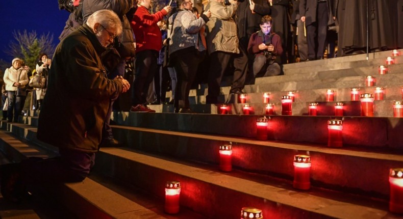 Un homme prie sur les marches de la cathédrale orthodoxe de Timisoara à l'occasion d'une marche au flambeau commémorant le début du soulèvement contre le régime du dictateur roumain Nicolae Ceausescu, il y a trente ans, à Timisoara (ouest), berceau de la révolution de  1989.