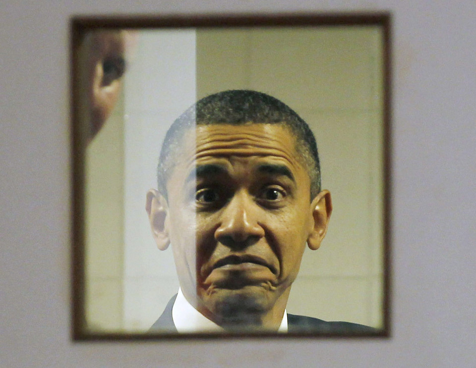 U.S. President Barack Obama reacts as he sees photographers through a door window from backstage as he waits to deliver remarks at the U.S.-India business council and entrepreneurship summit in Mumbai, India, November 6, 2010.