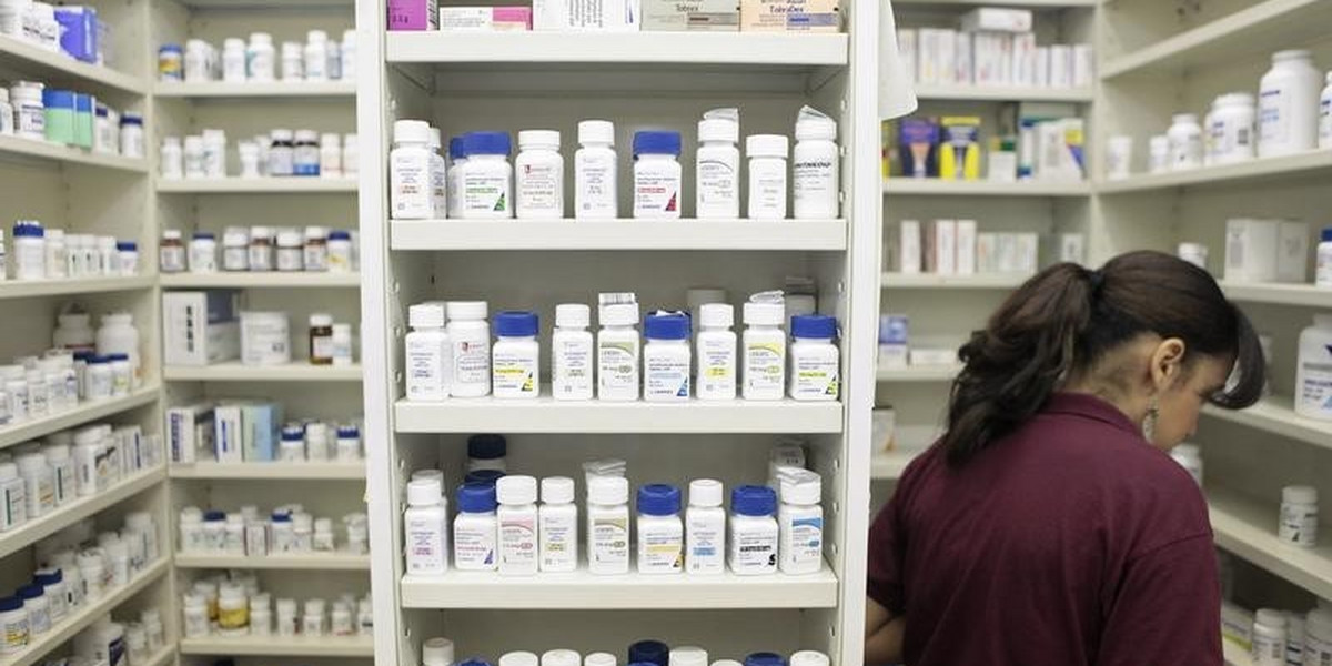 A pharmacy employee looks for medication as she works to fill a prescription.