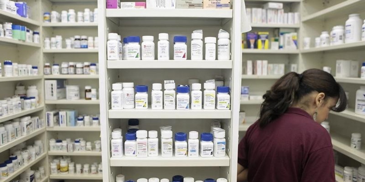 A pharmacy employee looks for medication as she works to fill a prescription.