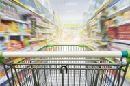 Supermarket aisle with empty green shopping cart