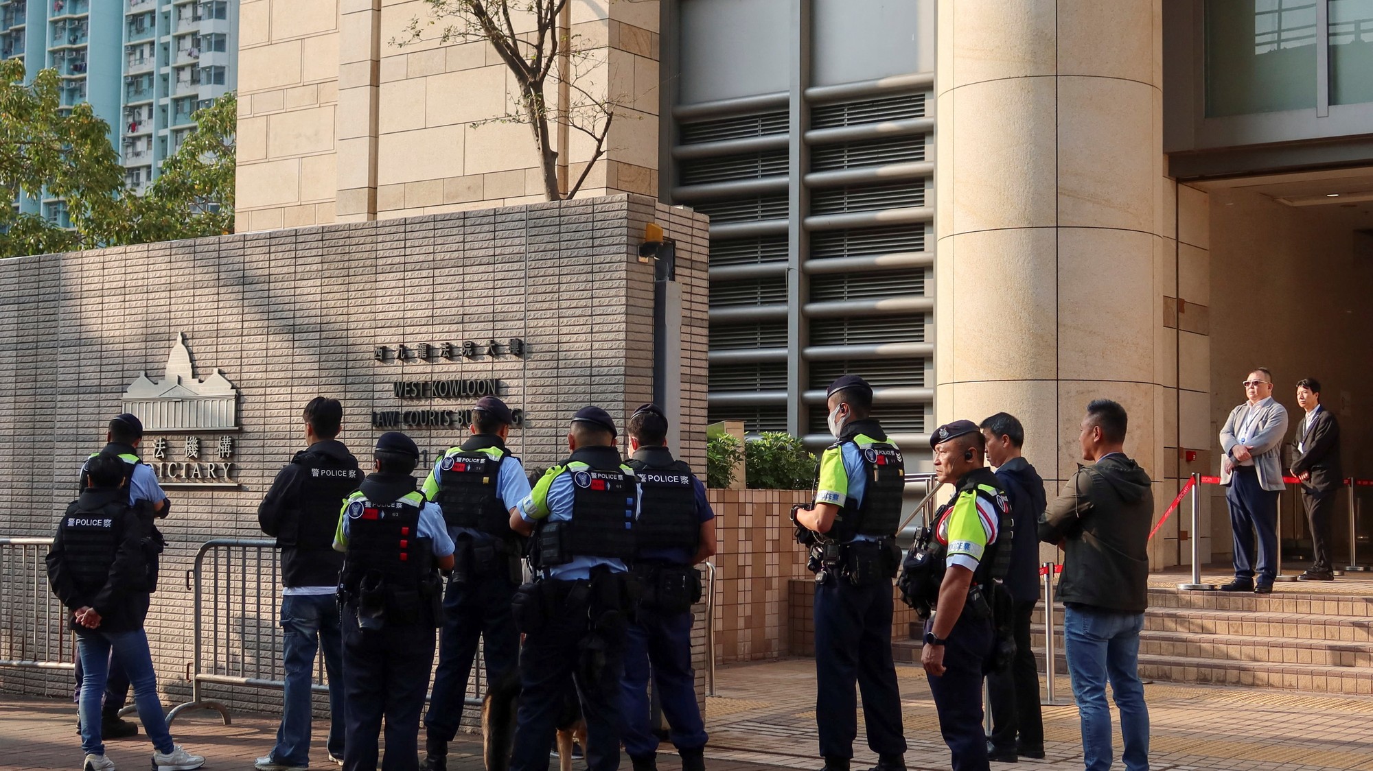Polícia stráži dvanásť prodemokratických aktivistov, ktorí sa odvolávajú proti svojim rozsudkom a trestom v prelomovom prípade týkajúcom sa národnej bezpečnosti v budove súdu West Kowloon Magistrates' Courts v Hongkongu.