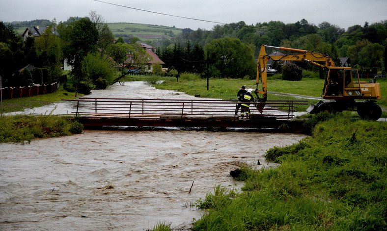 Strażacy obciążają betonowymi płytami most na wezbranej rzece Stupnica w Birczy, chcąc uchronić go przed zerwaniem przez wodę. Fot. PAP/Darek Delmanowicz