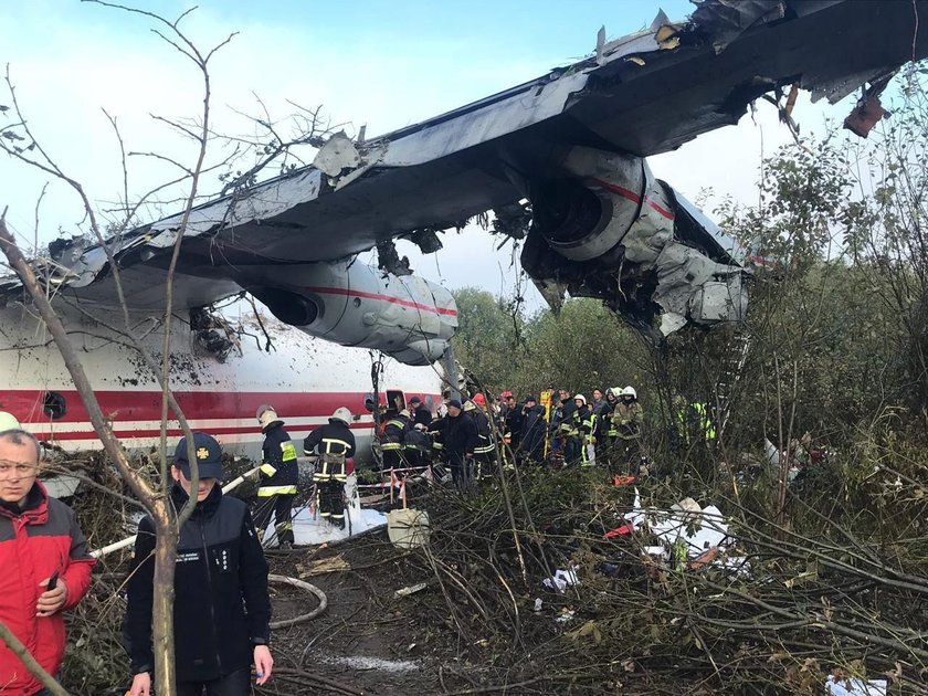 Members of emergency services evacuate a wounded person at the site of the Antonov-12 cargo airplane