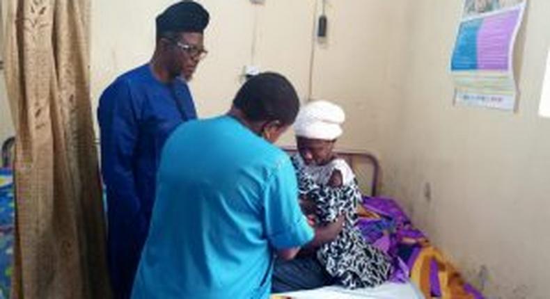Chairman of Ido-Osi Local Government Council, Dr. Sola Ogunsina in cap with the hospital attendant, mother and the twins on hospital bed.