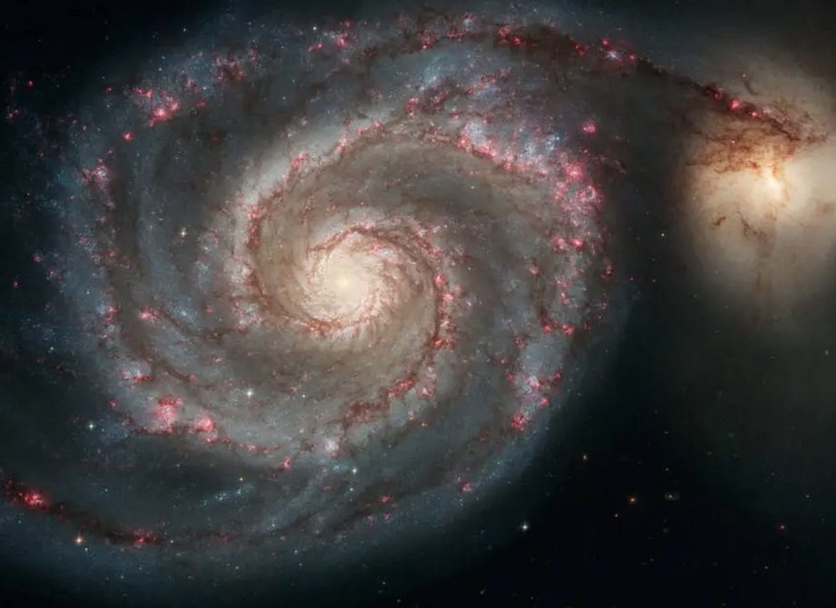 Galaktyka spiralna M51 pokazana na zdjęciu wykonanym przez Hubble'a w 2005 roku. Inna mała, żółtawa galaktyka widoczna jest na najbardziej zewnętrznym krańcu jednego z ramion