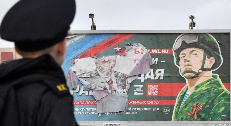 A military cadet stands in front of a billboard promoting contract army service in Saint Petersburg on October 5, 2022.OLGA MALTSEVA/AFP via Getty Images