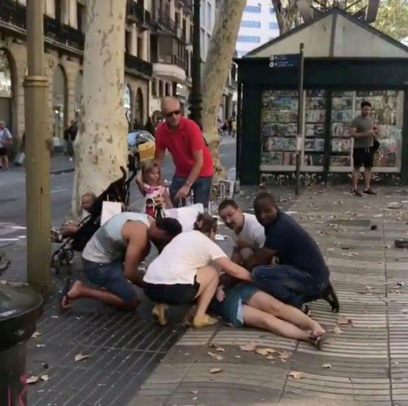 People help an injured woman after a van crashed into pedestrians near the Las Ramblas avenue in cen