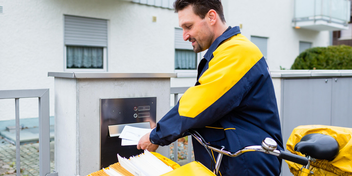 Postman delivering letters to mailbox of recipient