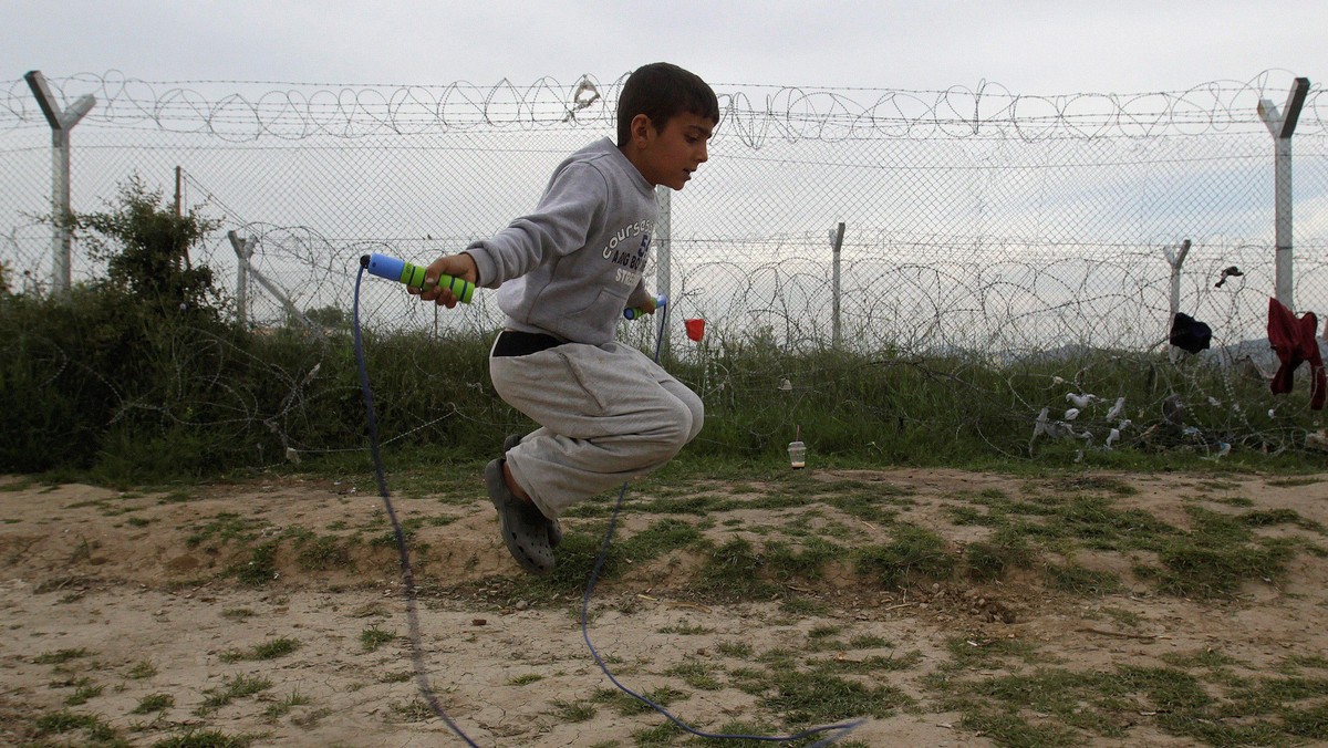 A boy jumps a rope next to a border fence at a makeshift camp for refugees and migrants at the Greek-Macedonian border near the village of Idomeni