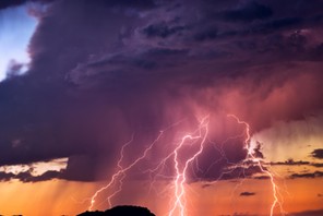 Lightning bolts strike from a sunset storm