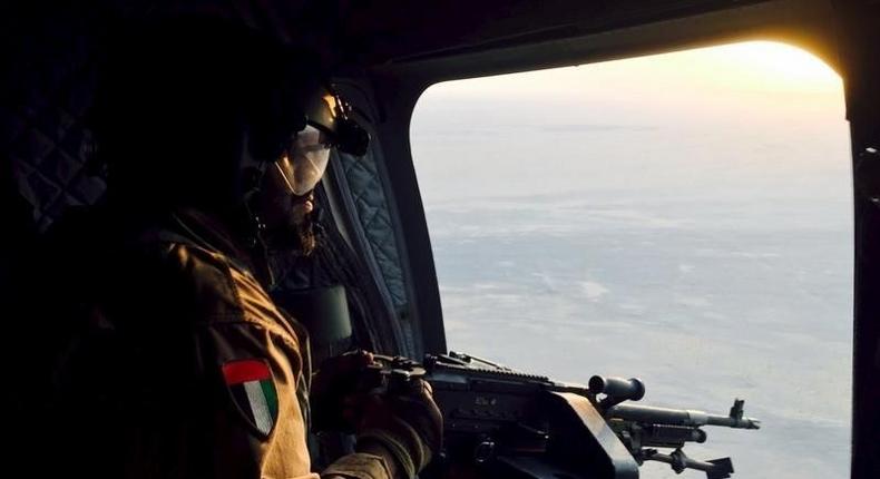 A soldier from the United Arab Emirates armed with a machine gun watches over Yemeni territory while riding a Chinook helicopter en route to a Saudi-led coalition air base in the kingdom September 17, 2015. Armed with high-tech Western weaponry, Gulf Arab soldiers are fighting with newfound determination against what they see as the expanding influence of Iran, their non-Arab and Shi'ite Muslim arch-foe, in a war that has ravaged Yemen for six months. The oil-producing province of Marib has become a key battlefield between Iranian-allied Houthi militia and a coalition of Yemenis and Emirati, Saudi and Bahraini troops. Marib forms a gateway to the Yemeni capital Sanaa 120 km (75 miles) to the west, which the Houthis seized last year. REUTERS/Abdelhadi al-Ramahi - RTS1NIC