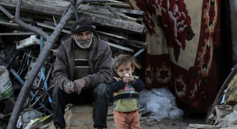 A Palestinian man sits with his son outside their house in an impoverished area in the southern Gaza Strip town of Khan Yunis on February 19, 2017