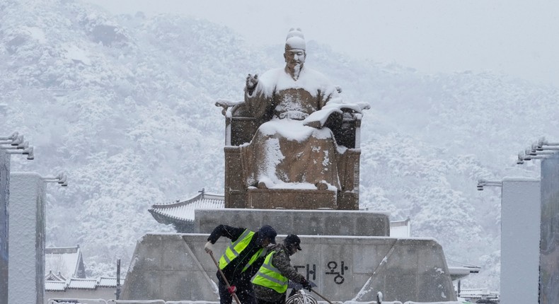 Workers clean snow in front of the statue of King Sejong at Gwanghwamun Square in Seoul, South Korea.AP Photo/Ahn Young-joon