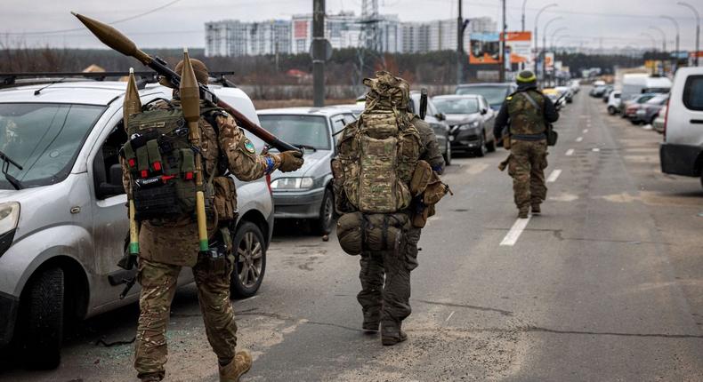 Ukrainian troops carry rocket-propelled grenades and sniper rifles toward the city of Irpin, northwest of Kyiv, March 13, 2022.