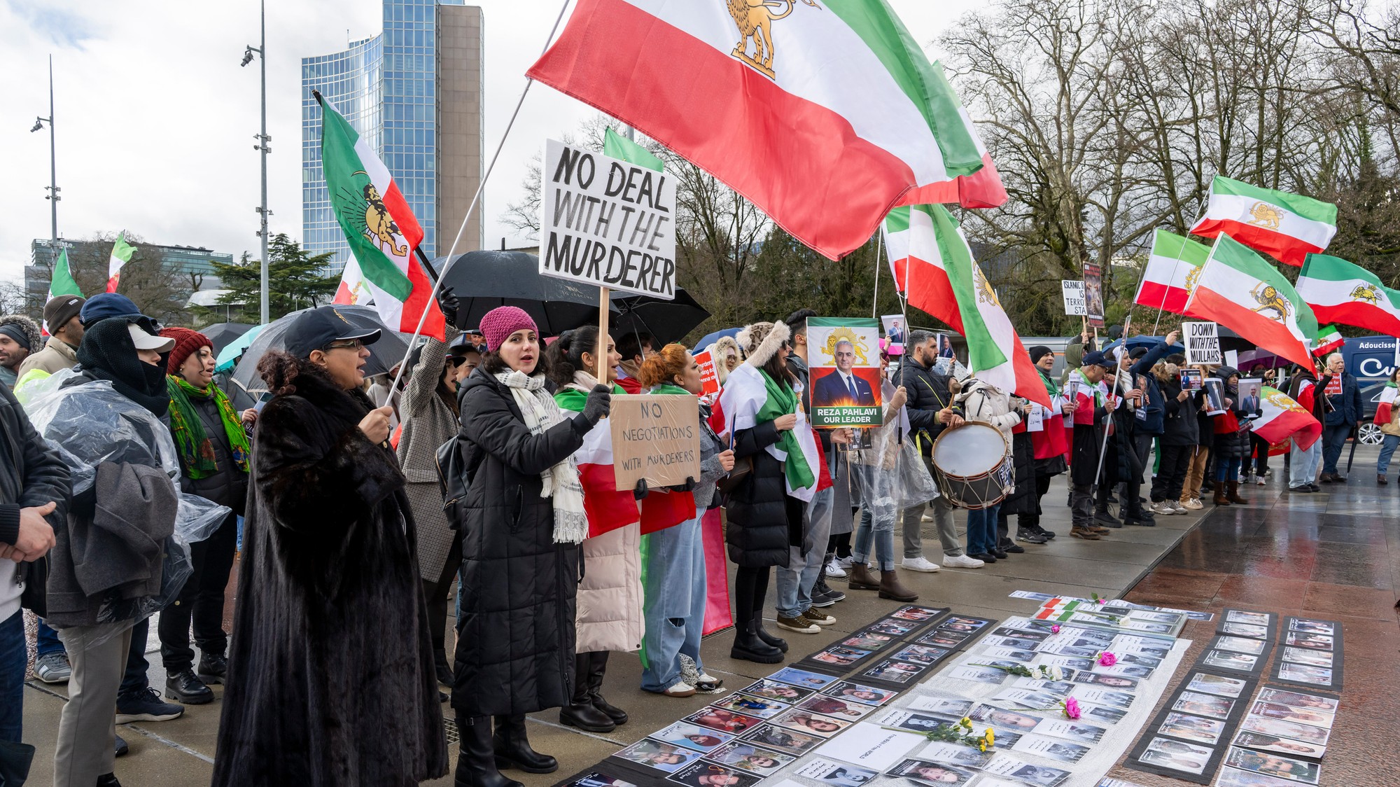 Iránski demonštranti držia transparenty a portréty počas demonštrácie pred budovou Organizácie Spojených národov pred nepriamymi jadrovými rokovaniami medzi Spojenými štátmi a Iránom v Ženeve.