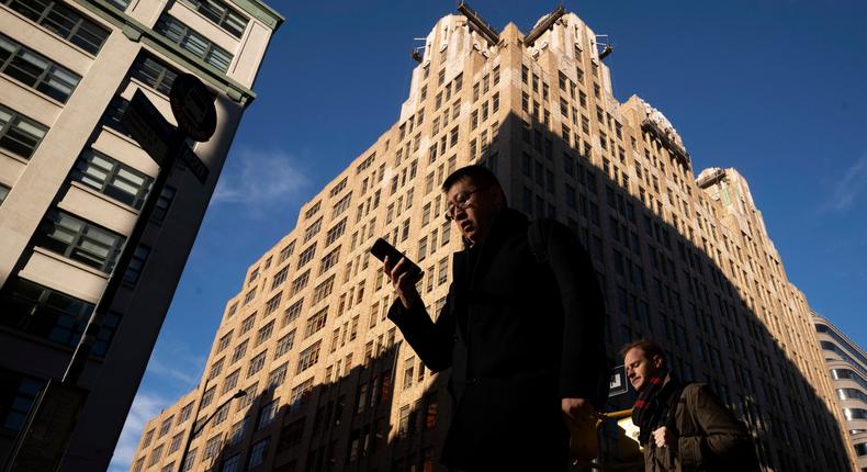 FILE - In this Dec. 17, 2018, file photo people walk by a building in New York. You carry your smartphone everywhere. But the way you use it could leave you vulnerable to specific forms of identity theft, including robocall scams and hackers looking to hijack your phone number. (AP Photo/Mark Lennihan, File)