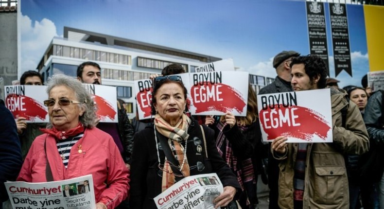 Protesters hold the Cumhuriyet daily newspaper, with the headline reading, Coup against opposition, as others hold placards reading Never submit in front of the newspaper's headquarters on October 31, 2016 in Istanbul