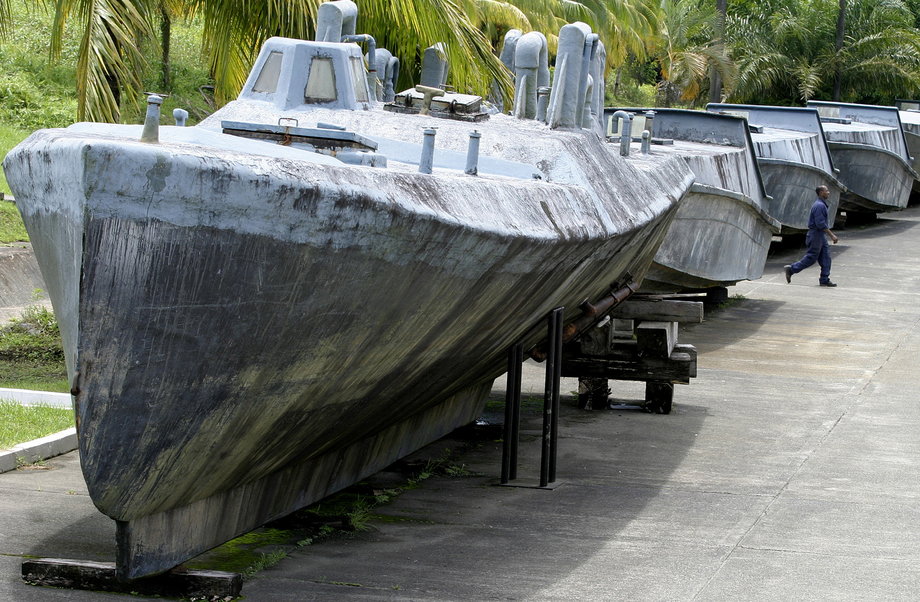 A man walks between a makeshift fiberglass submarine (front) and speedboats, used to smuggle cocaine used by Colombian drug traffickers, in Buenaventura June 24, 2008. Colombians who thought they had seen everything in the war on drugs were treated to something new this year: cocaine smuggling in a submarine.