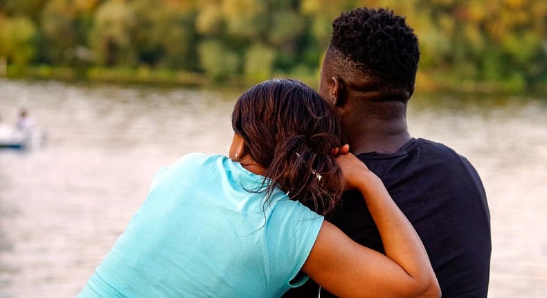 A lady and a man sitting by the river