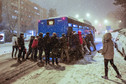 Pasażerowie pchający autobus, który utknął w śniegu
