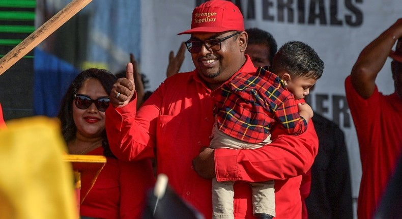 Irfaan Ali holds his son as he arrives at a campaign rally in Lusignan, Guyana on February 29, 2020