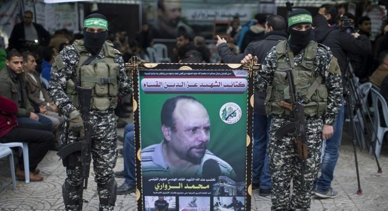 Members of the Ezzedine al-Qassam Brigades, the military wing of the Palestinian Islamist movement Hamas, hold a banner bearing a portrait of one of their leaders, Mohamed Zaouari, who was murdered in Tunisia, during a ceremony in his memory